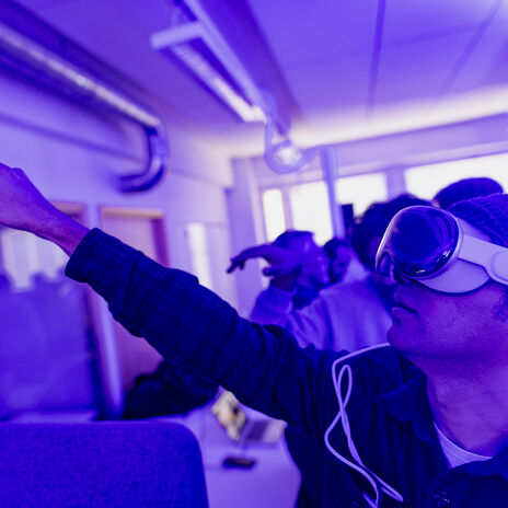 A person pointing to top left corner with VR glasses on.