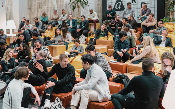 People attending an event, sitting down and chatting, about 50 of them
