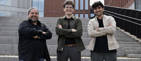 Three men, the Taru Tech team, smiling at the camera in front of a building at Aalto University